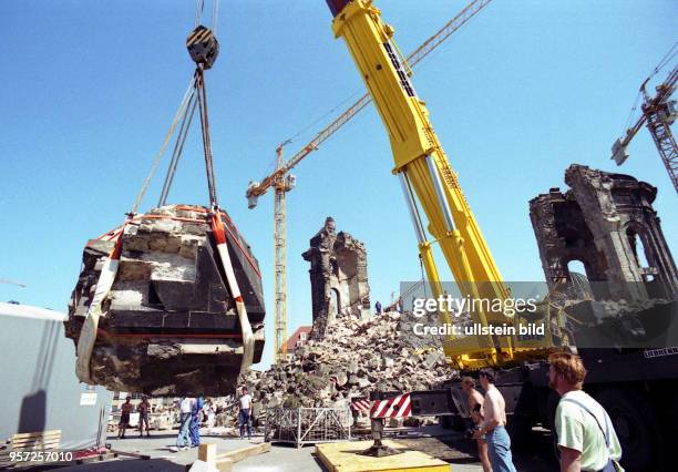 Ein großes Trümmerstück wird mit einem Kran an der Ruine der Frauenkirche in Dresden geborgen, an der die Sicherungsarbeiten und die Beräumung...