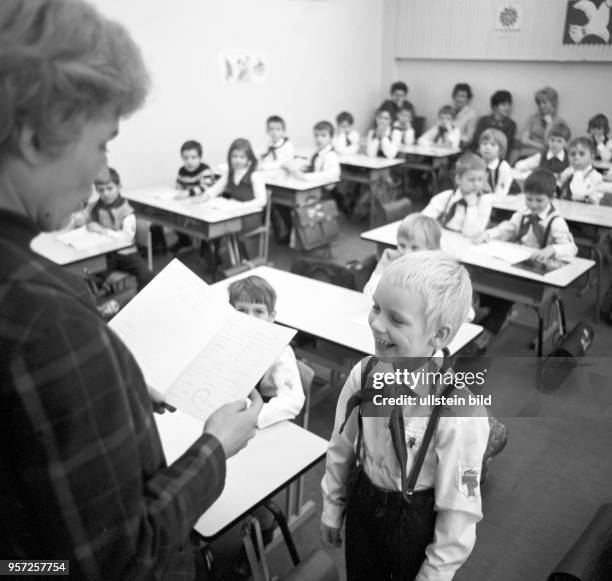 Schüler einer unteren Klasse tragen zur Zeugnisübergabe im Klassenzimmer einer Schule in Berlin ihre Pionierkleidung und das Halstuch, undatiertes...