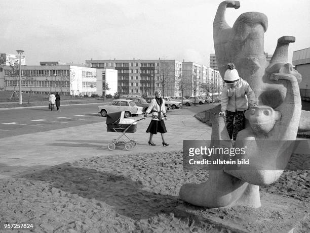 Ein kleines Kinder erklimmt zur Freude seiner Mutter eine Affen-Skulptur, die als Klettergerüst auf einem Spielplatz im Hof einer modernen...