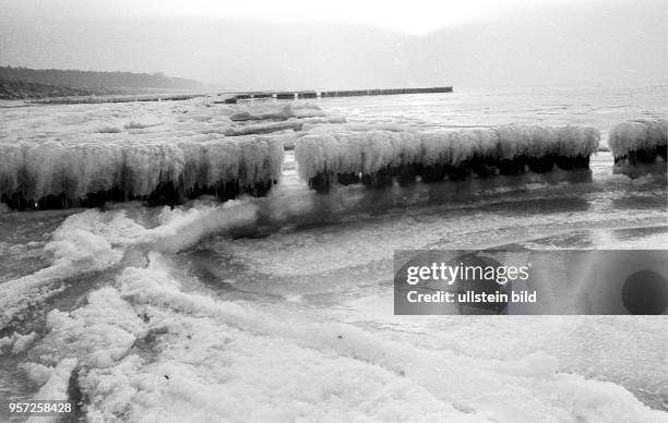 Eispanzer haben die Holzbuhnen am winterlichen Strand von Ahrenshoop an der Ostsee überzogen, aufgenommen im Januar 1985. Auch in den Wintermoaten...