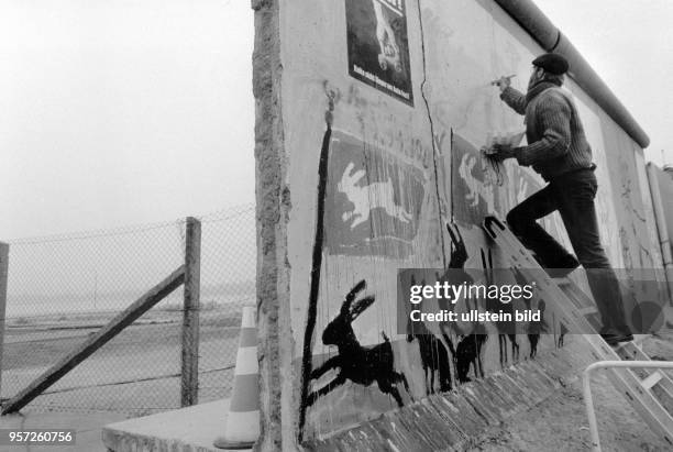 Ein Mann bemalt am einen Teil der Berliner Mauer am Potsdamer Platz. Die Grenzöffnung, bzw. Der Mauerfall, war am fast lapidar in einer...