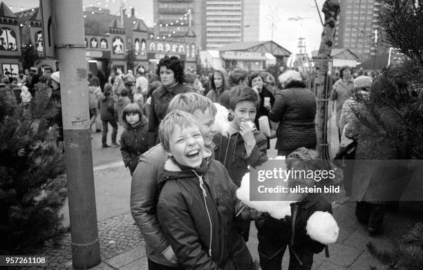 Kinder mit Zuckerwatte laufen auf dem Ostberliner Weihnachtsmarkt am Alexanderplatz am Tag seiner Eröffnung , aufgenommen im November 1982. Foto :...