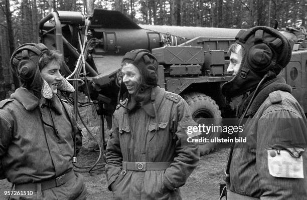 Soldaten der DDR mit Panzerhaube unterhalten sich vor einer Startrampe mit Rakete während einer Manöverübung der Flugabwehrraketentruppen,...