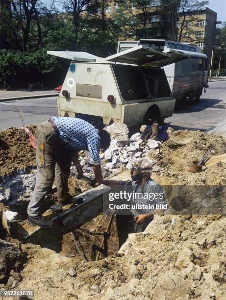 Arbeiter arbeiten mit Schutzmaske in einer Baugrube in einer Straße in Berlin-Pankow an einem Gasrohr, undatiertes Foto von 1980. Bereits 1977 hatte...