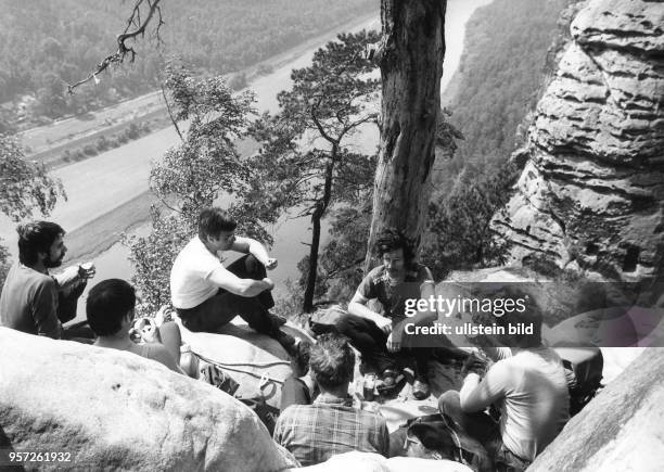 Bergsteiger sitzen im Juli 1984 nach einer Klettertour zur Brotpause an einem Fels der Bastei 120 Meter über der Elbe. Mehr als 1060 Gipfel bieten in...