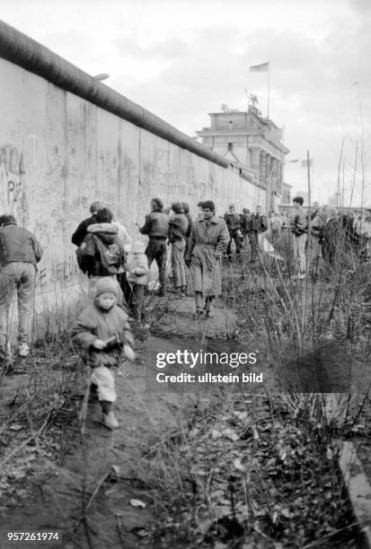 Menschen auf der West-Seite der Mauer von Berlin am Brandenburger klopfen mit Hämmern Steine aus der Betonmauer, aufgenommen am . Die Grenzöffnung,...