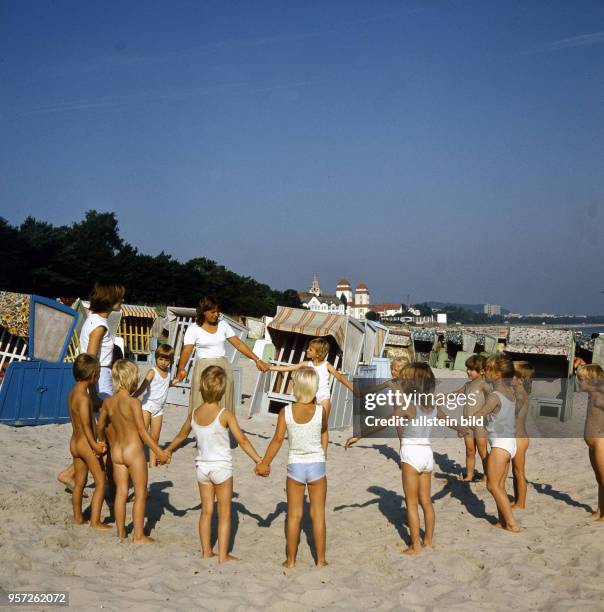 Spielende Kinder am Sandstrand von Binz auf der Insel Rügen an der Ostsee, aufgenommen im Sommer 1987.