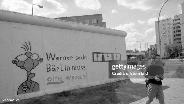 Eine Zeichnung der Comic-Figur "Werner" und der Schriftzug "Werner sacht: Bärlin muss oins werden" an der Berliner Mauer am ehemaligen Grenzübergang...