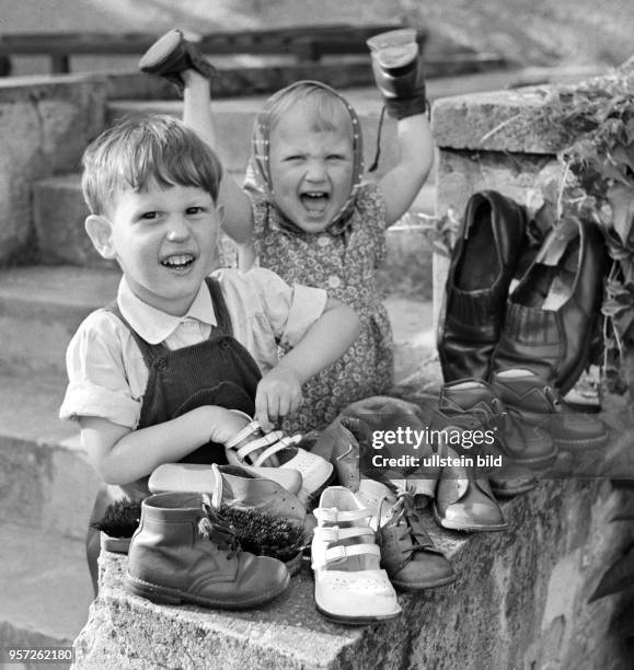 Ein Mädchen und ein Junge helfen im Haushalt und putzen Schuhe, undatiertes Foto von 1958.