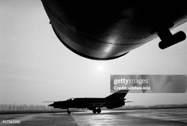 Jagdflieger der NVA bei der Ausbildung, aufgenommen im Jahr 1984. Ein Jagdflugzeug steht auf der Start- bzw. Landebahn.