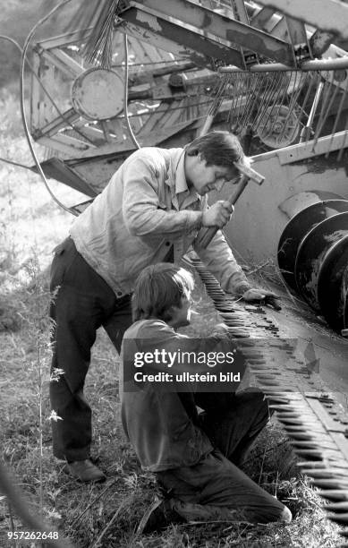 Ernte von Getreide im Bezirk Mageburg - Arbeiter reparieren einen Mähdrescher ,aufgenommen 1984. Foto : Reinhard Kaufhold