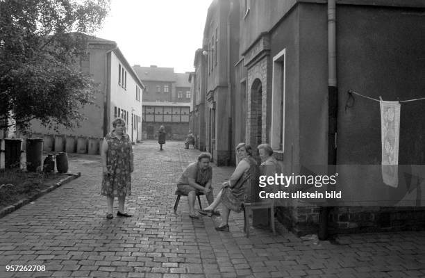 Frauen haben sich Stühle auf den Hof gestellt und "tratschen" in der Wohnsiedlung der Kupferhütte Helbra, aufgenommen im Frühjahr 1984. Der...