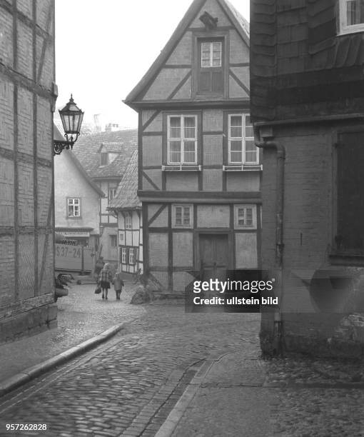 Blick in eine Straße mit Fachwerkhäusern am Quedlinburger Schlossberg, aufgenommen um 1960 im Winter. Das rekonstruierte Fachwerkhaus im...