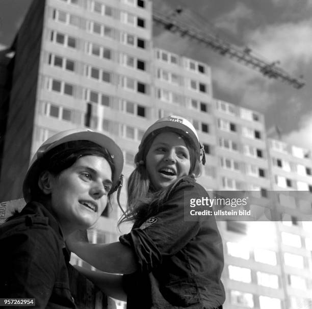 Junge Frauen in den blauen Blusen der FDJ und durch einen Bauhelm geschützt auf einer Baustelle am Leninplatz , aufgenommen 1969. Hier entstehen in...