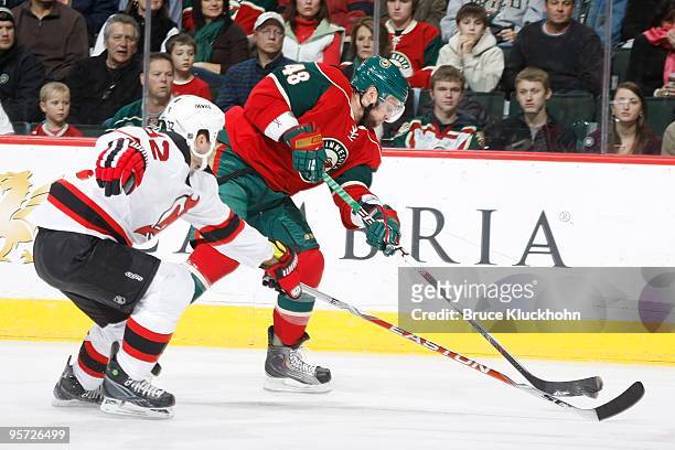 Guillaume Latendresse of the Minnesota Wild passes the puck while Matthew Corrente of the New Jersey Devils defends during the game at the Xcel...