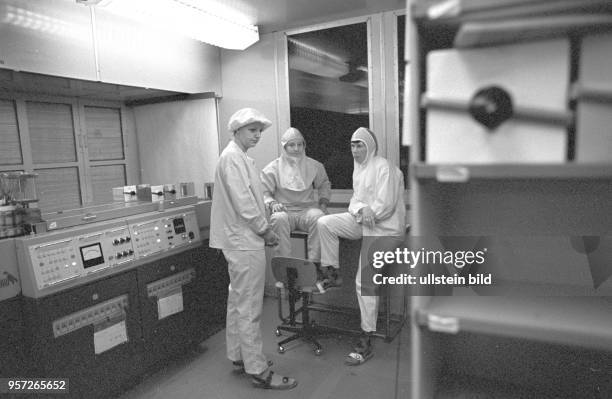 Im Reinraum und in Schutzkleidung diskutieren Techniker im Kombinat Mikroelektronik Erfurt die Probleme der Produktion, undatiertes Foto von 1981.