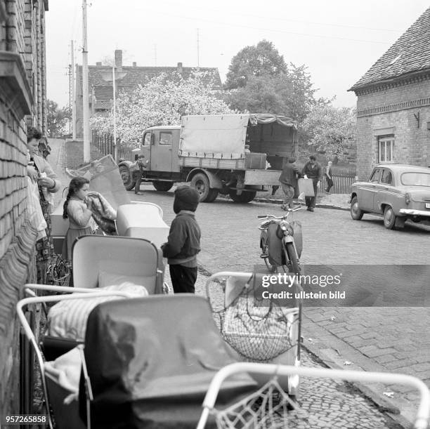 Viele Kinderwagen stehen vor einem Backsteingebäude, in dem die Schwesternstation untergebracht ist, aufgenommen im Frühjahr 1966 in Polleben, Kreis...