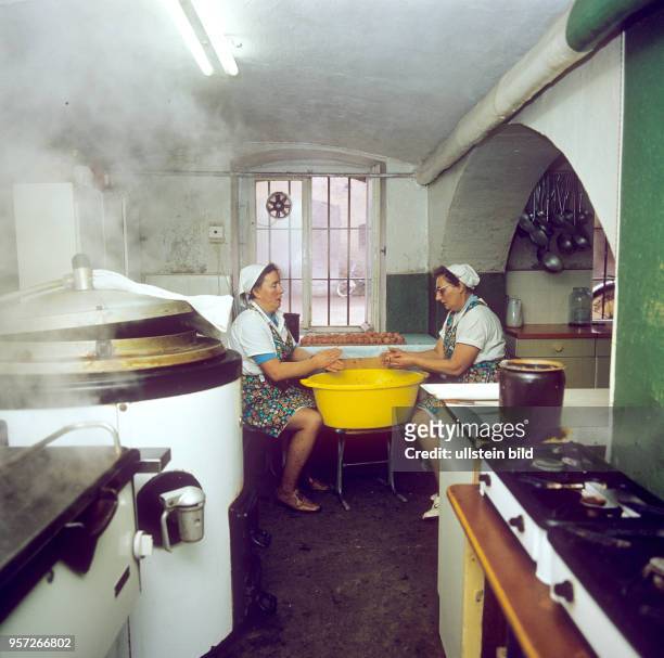 Zwei Frauen formen in einer Küche einer Versorgungseinrichtung Fleischbällchen für das Mittagessen, undatiertes Foto von 1978.