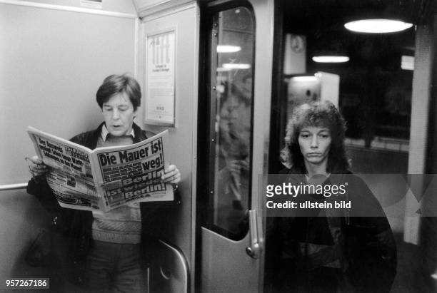 Eine Frau betritt am Morgen des 10. November 1989 in Berlin einen U-Bahnwaggon, in dem ein Mann eine BZ liest. Mit großen Lettern verkündet die...