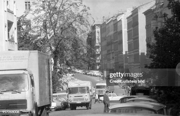 Strassenszene in der Hufelandstrasse im Stadtteil Prenzlauer Berg in Berlin in der Wendezeit, aufgenommen im Sommer 1990. Am Straßenrand parken Pkw.