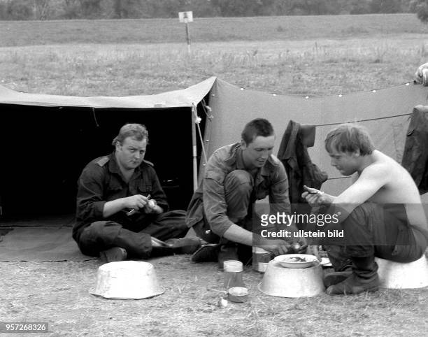 Soldaten der Nationalen Volksarmee beim Essen in einem Feldlager, aufgenommen bei der Ausbildung von Bodentruppen der Nationalen Volksarmee der DDR...