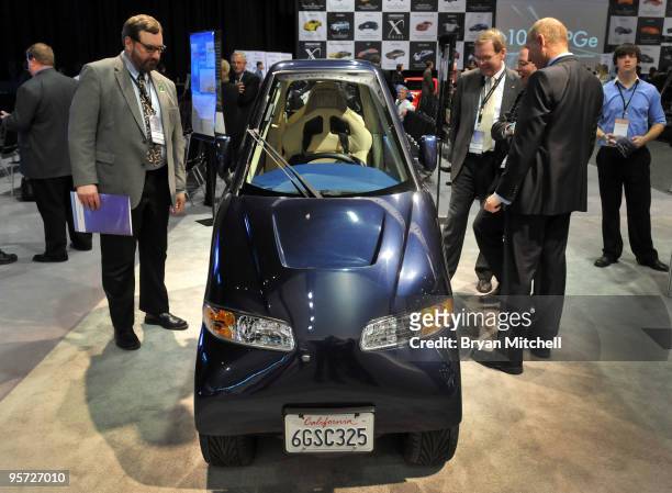 Members of the media look at the Commuter Cars Tango electric car on display during the press preview for the world automotive media North American...