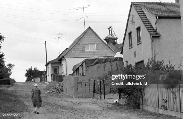 Eine ältere Frau spaziert durch Wettelrode im Mansfelder Land, aufgenommen am . Im Hintergrund der Förderturm des Röhrigschachtes Wettelrode. Der...