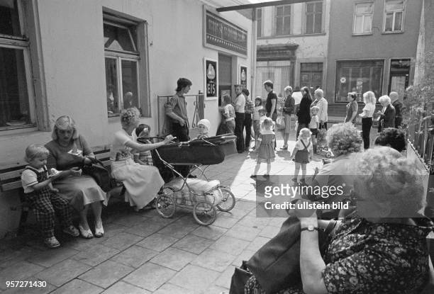 Mütter mit Kinderwagen und Kinder sowie ältere Einwohner vor einer Eisdiele in Lutherstadt Eisleben, vor der eine lange Schlange wartender Kunden...