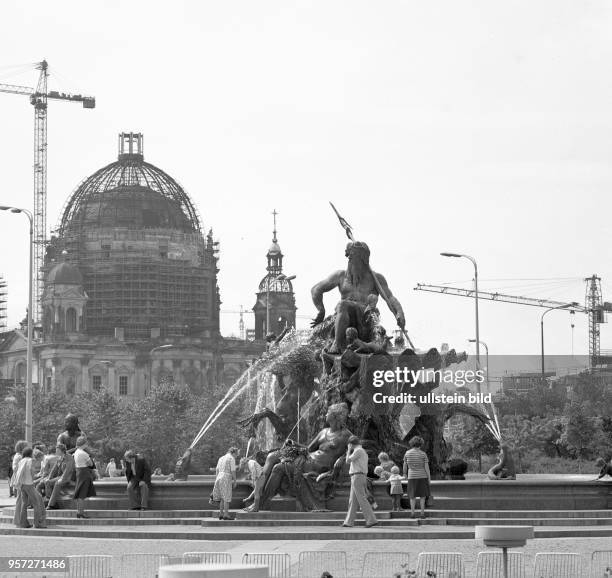 Der Neptunbrunnen am Roten Rathaus in Berlin-Mitte, im Hintergrund der Berliner Dom und Bauarbeitern zur Sanierung des historischen Bauwerkes.