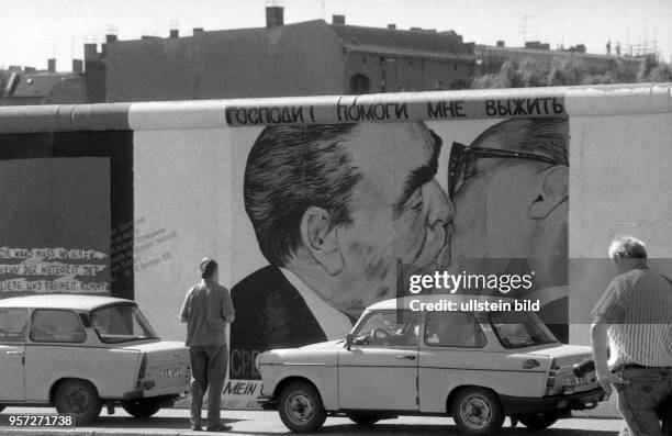 Ein Pkw Trabant steht an der Mühlenstrasse in Ostberlin vor dem Bild Bruderkuss , gemalt vom russischen Maler Dmitri Waldimirowitsch Wrubel ,...