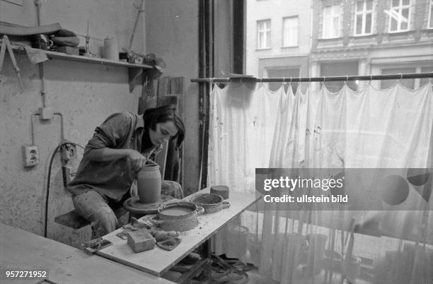 Eine Töpferin bei der Arbeit in einer einfachen Werkstatt eines Ladenschäftes in einem Altbau in der Nähe der Ackerstraße in Berlin-Mitte,...