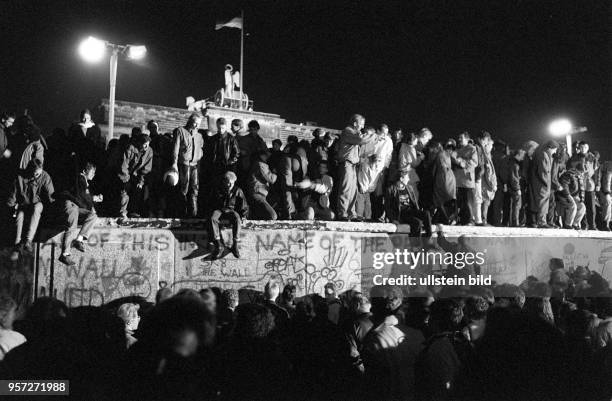 Einen Tag nach der Grenzöffnung in Berlin feiern tausende Menschen auf, vor und hinter der Berliner Mauer am Brandenburger Tor, aufgenommen am auf...