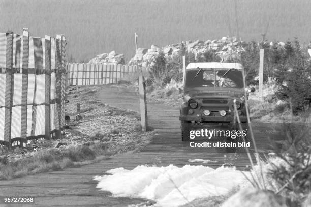 Ein Geländewagen der NVA-Grenztruppen bei der Kontrollfahrt auf dem Kolonnenweg neben dem Metallgitterzaun der DDR-Grenzanlagen im Harz bei...