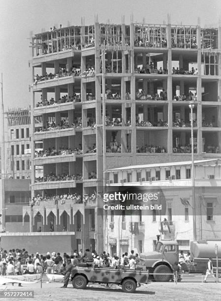 Zuschauer am Rande der Straße und in den Etagen eines im Rohbau stehenden Gebäudes verfolgen eine Militärparade der libyschen Streitkräfte in Bengasi...