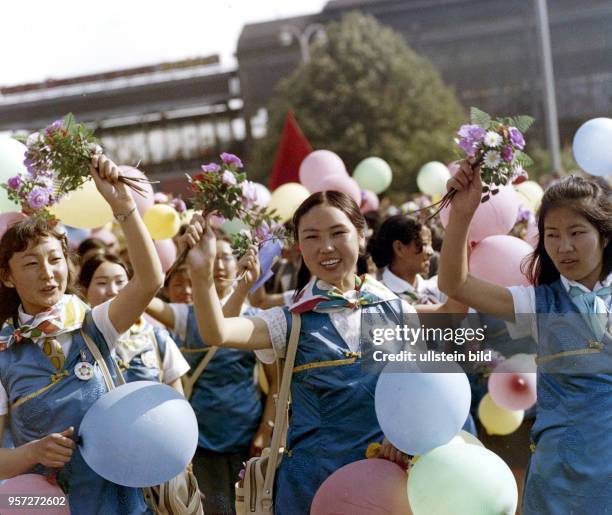 Junge Frauen aus der Mongolischen Volksrepublik laufen mit Blumen und Luftballons in den Händen über die Friedrichstraße in Berlin-Mitte, aufgenommen...