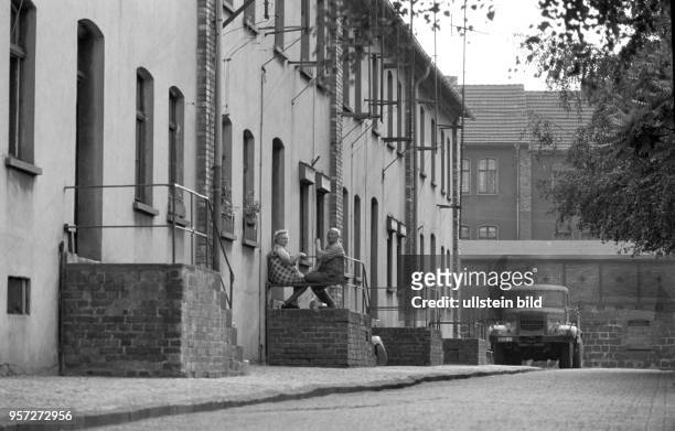 Eine älteres Paar sitzt auf einer Bank im Geländer zum Haus in der Wohnsiedlung der Kupferhütte Helbra, ein LKW ist am Straßenrand abgestellt und...