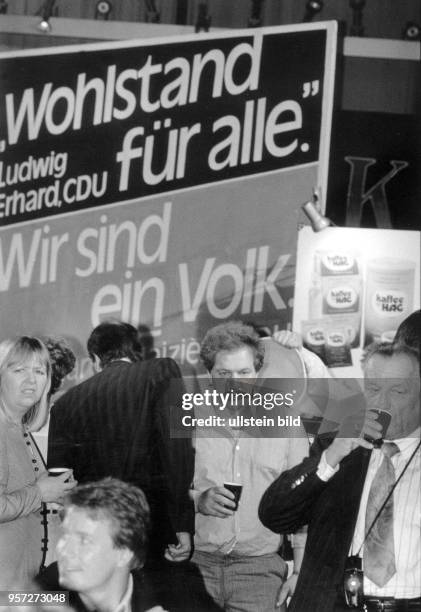 Menschen vertreiben am Abend der Wahlen zur Volkskammer der DDR im Ostberliner Palast der Republik ihre Müdigkeit mit einem Becher Kaffee,...