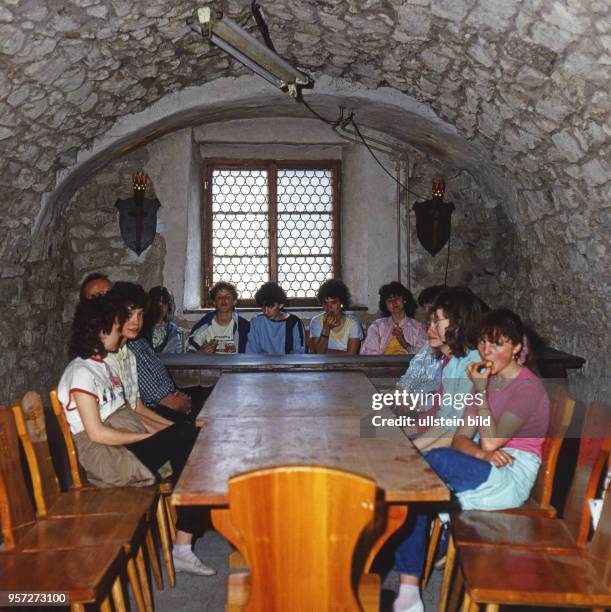 In der Burg Hohnstein in der Sächsischen Schweiz befand sich eine der größten Jugendherbergen der DDR - hier Jugendliche an rustikalen Möbeln unter...