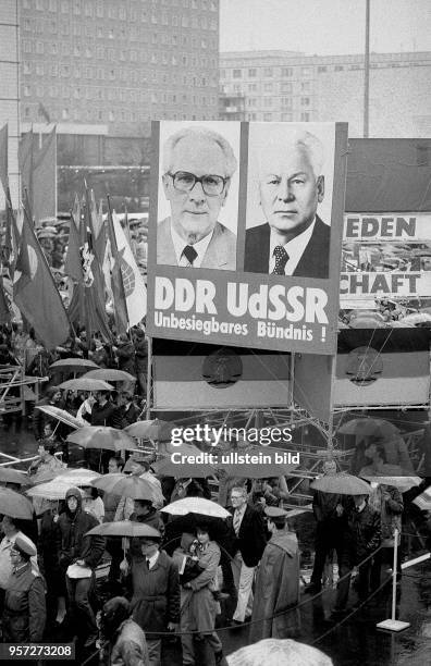 Die Bildnisse von DDR- Partei- und Staatschef Honecker und des sowjetischen Staats- und Parteichef Tschernenko werden neben Plakaten, Losungen und...