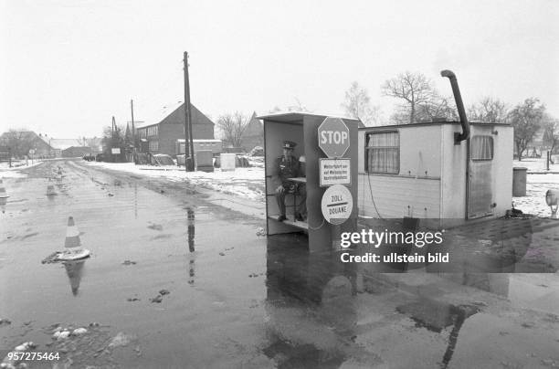 Ein DDR-Grenzsoldaten sitzt in einem kleinen Häuschen am provisorisch eingerichteten Grenzübergang zwischen Böckwitz in der DDR und dem Nachbarort...