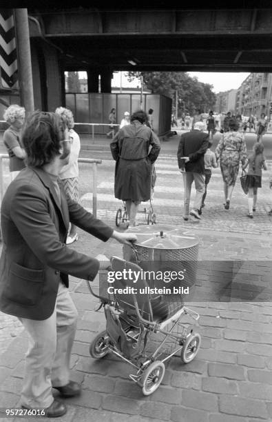 Ein Mann transportiert die neue Trommel für die Waschmaschine per Kinderwagen über die Schönhauser Allee, aufgenommen im Juni 1976 im Berliner...