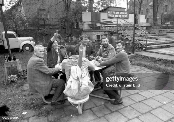 Eine Gruppe von Männern beim geselligen Biertinken im Freien, aufgenommen im Mai 1983 in Gerbstedt. Im Hintergrund ist die Losung "Alles für das Wohl...