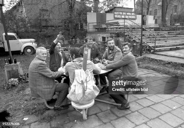 Eine Gruppe von Männern beim geselligen Biertinken im Freien, aufgenommen im Mai 1983 in Gerbstedt. Im Hintergrund ist die Losung "Alles für das Wohl...