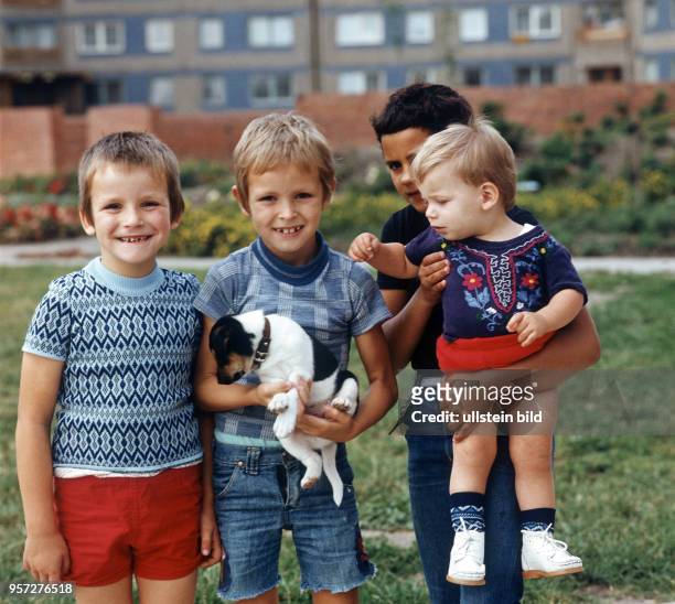 Vier Kinder und ein kleiner Hund posieren im Neubaugebiet Halle-Neustadt, undatiertes Foto von 1982.