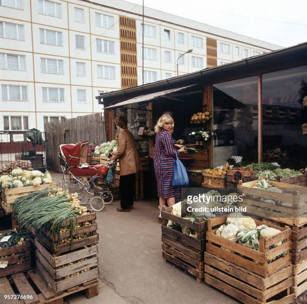 In Kisten vor einem Gemüseladen im Neubaugebiet Halle-Neustadt liegen Blumenkohl, Zwiebeln und andere Gemüse, undatiertes Foto von 1982.
