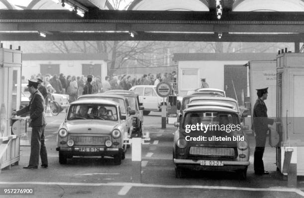 Lange Fußgängerschlangen und Reihenweise Fahrer mit Trabant-Pkw, die diszipliniert am Grenzübergang Bornholmerbrücke auf die Abfertigung durch die...