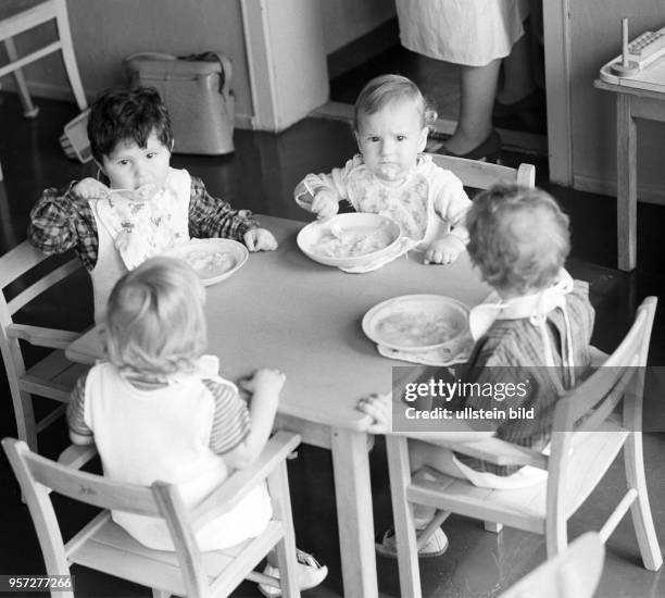 Vier Kinder beim Essen an einem Tisch in einem Kindergarten in Berlin-Treptow, aufgenommen im August 1968.