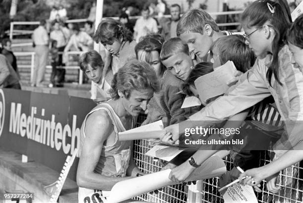 Der Europameister Hagen Melzer vom SC Einheit Dresden verteilt anläßlich der 41. DDR-Meisterschaften der Leichtathletik Autogramme an Kinder,...