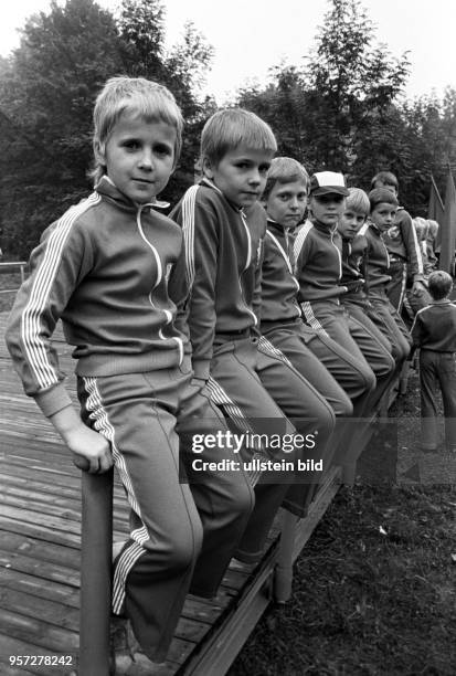 Jungs aus einem Sportverein hocken in ihren Traningsanzügen auf dem Geländer einer Bühne am beim traditionellen Spreewaldfest in Lübbenau .