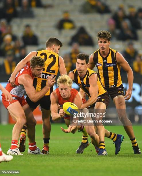 Isaac Heeney of the Swans handballs whilst being tackled by Jaeger O'Meara of the Hawks during the round eight AFL match between the Hawthorn Hawks...